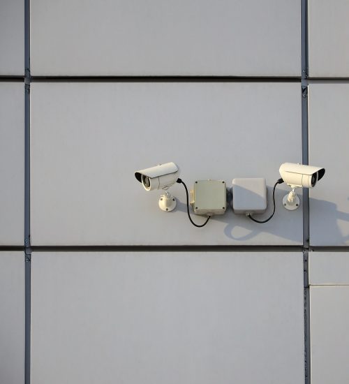 white-surveillance-camera-built-into-the-metal-wall-of-the-office-building.jpg